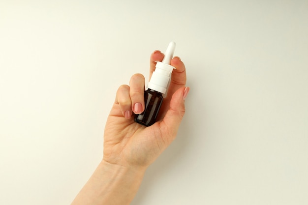 Female hand holds blank bottle of nasal spray on white background