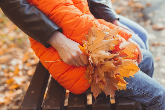 La mano femminile tiene un mazzo di foglie d'acero autunnali. stagione autunnale e concetto di natura.