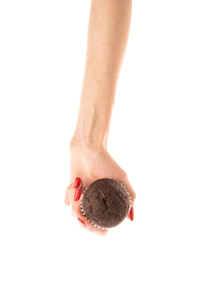 Female hand holds a brown chocolate cupcake isolated on white background