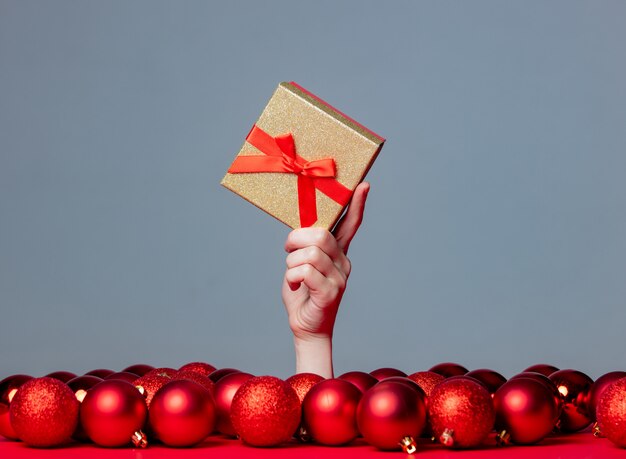 女性の手を保持しているつまらないもので灰色の背景にクリスマスgfitボックス