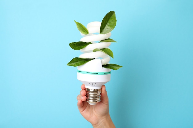 Photo female hand holds energy saving bulb on blue background