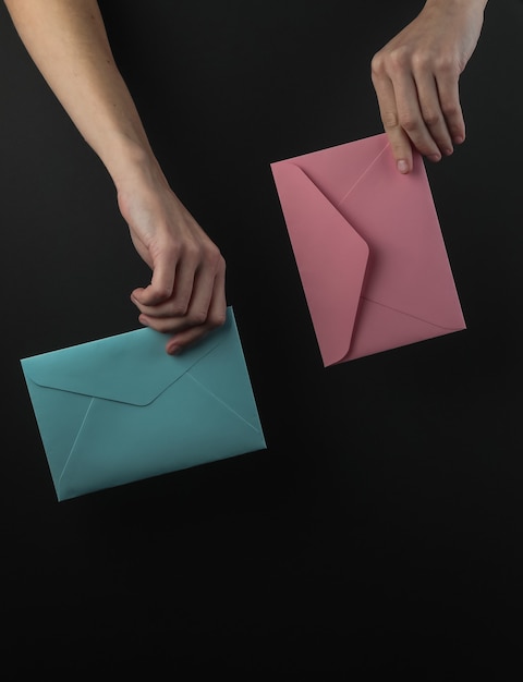 Female hand holds envelopes on a black background
