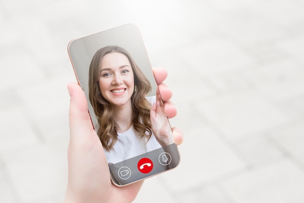 Female hand holds a mobile phone and talking to her girlfriend\
on video chat video calls conference