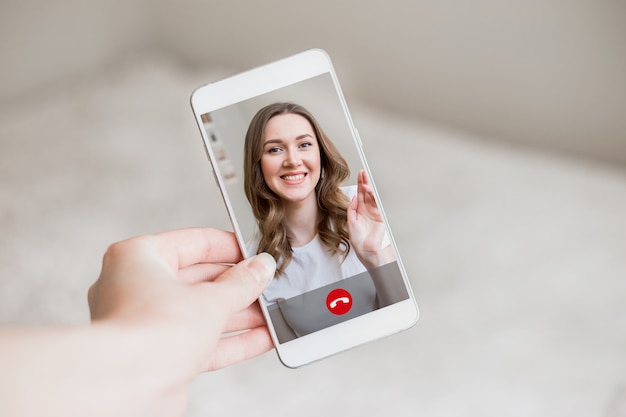 Foto una mano femminile tiene un telefono cellulare con una ragazza sullo schermo