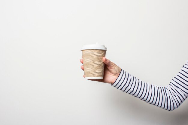 Female hand holds a paper cup on a white