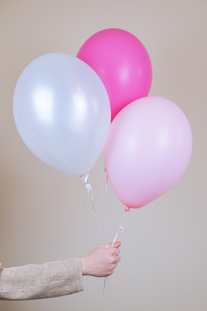 A female hand holds a pink helium balloon. The concept of holiday decorations, accessories for the children's holiday