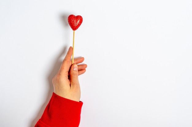 A female hand holds a shiny heart on a stick