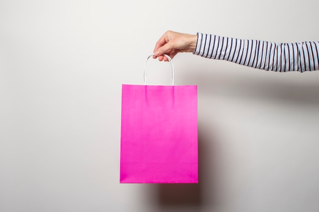 Female hand holds a shopping bag on a white. Concept shopping, discount, sale.