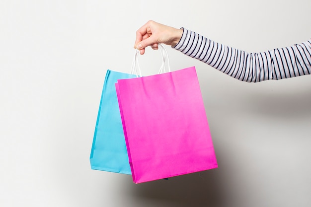 La mano femminile tiene i sacchetti della spesa su un bianco. shopping di concetto, sconto, vendita.