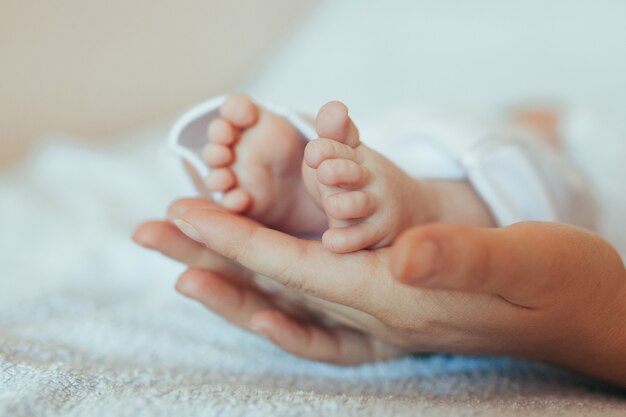 Female hand holds small baby legs