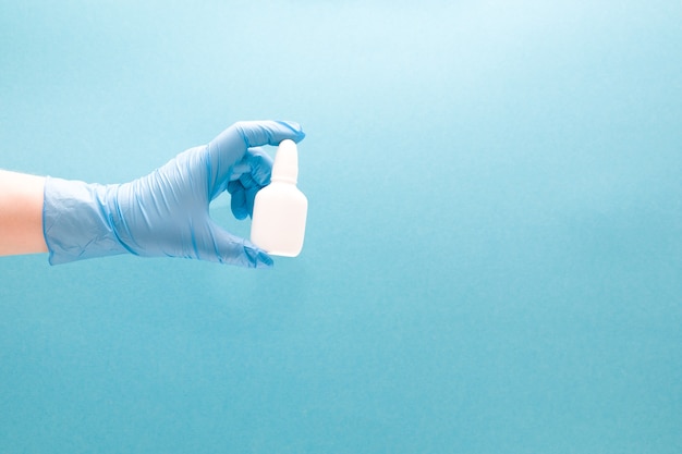 A female hand holds a white plastic bottle with medicine blue background copy space