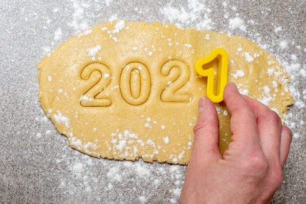 A female hand holds a yellow shape with the number one above the text to make the numbers from the text 2021