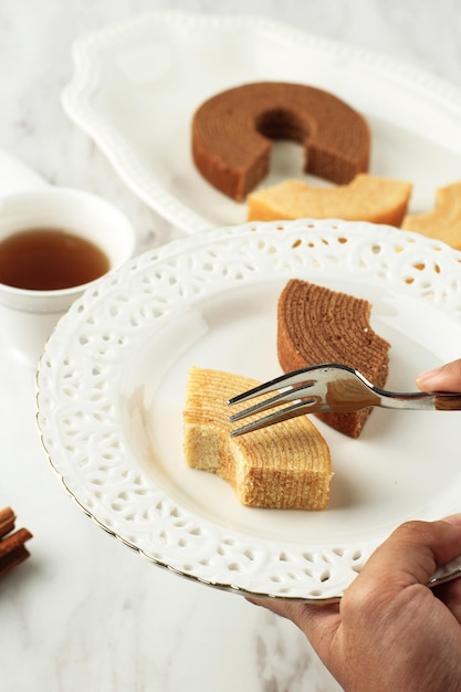 Female Hand Holed Plate with Slice of Baumkuchen or Tree Cake (Log Cake) is a Kind of Spit Cake from German Cuisine. It's also a Popular Dessert in Japan.