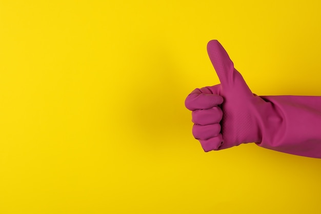 Female hand in housework glove on yellow background