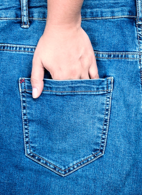  female hand is stuck in the back pocket of blue jeans