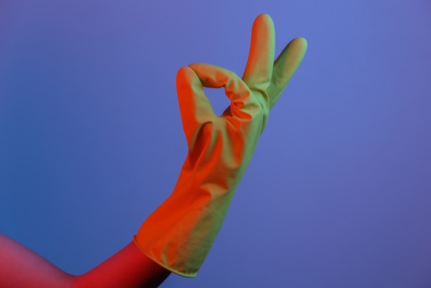 Female hand in latex glove shows okay symbol. Gradient neon light