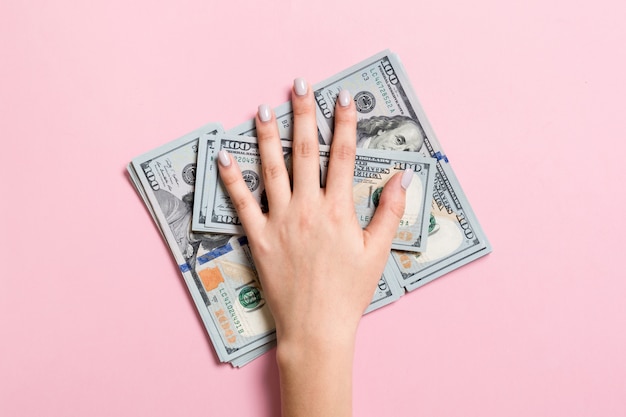 Female hand lying on stack of one hundred dollar bills. Saving money and wellbeing concept