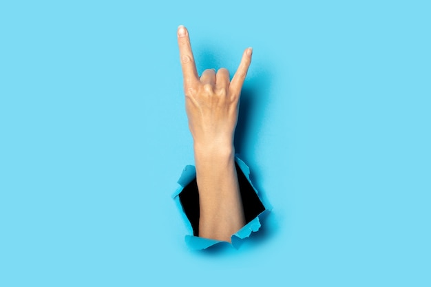 Photo female hand making a rock and roll gesture, party, goat on blue