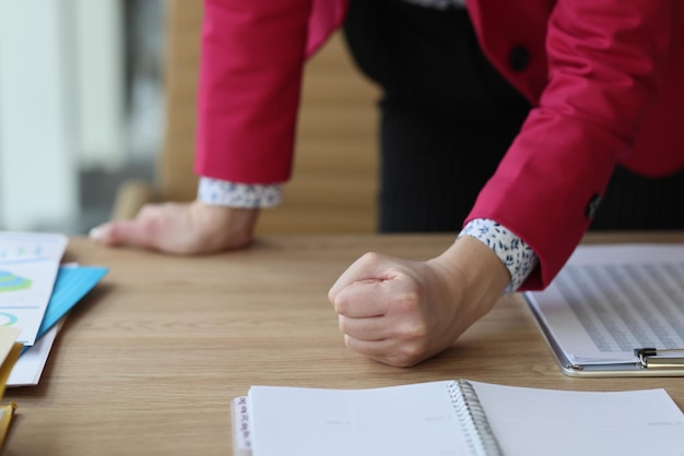 The female hand in the office beats a fist on the table a closeup concept requirement of salary