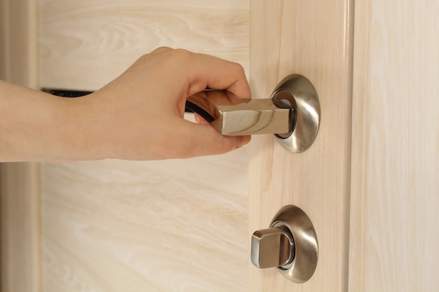 Female hand opens wooden door