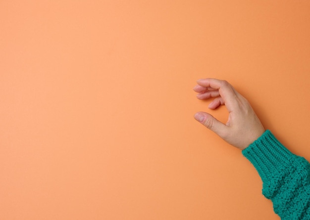 Female hand on an orange background, part of the body is holding the subject