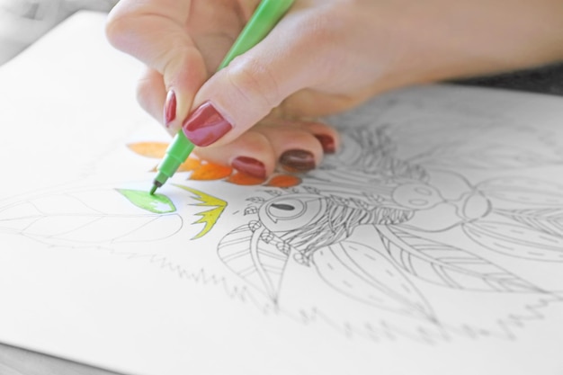 Photo female hand painting anti stress colouring with green felt pen