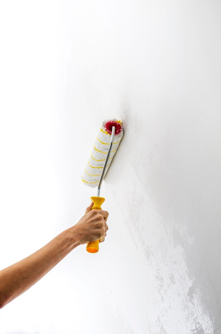 Photo female hand painting the wall