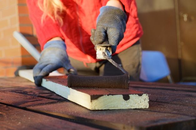 Female hand painting wood with paint roller