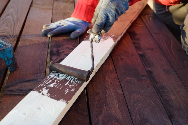 Female hand painting wood with paint roller