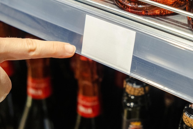 A female hand points to a price tag in a supermarket