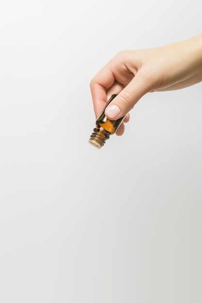 female hand pours essential aromatic oil from a small glass bottle