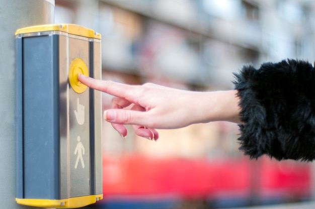 female hand pushing button for traffic light. Use traffic lights at the crossroads. Button of the mechanism lights traffic lights on the street. System control traffic light intersection close.