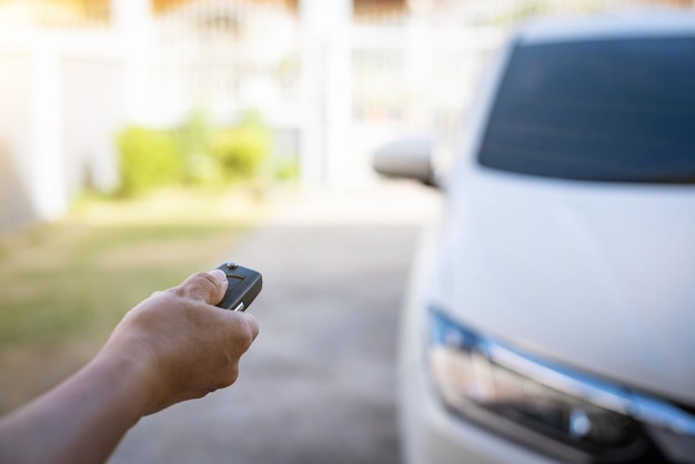 Female hand pushing remote key of white car