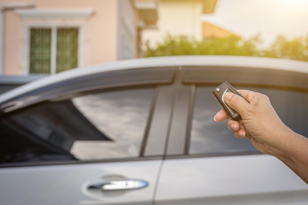 Female hand pushing remote key of white car