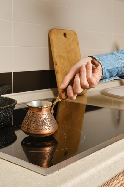 Female hand put turk coffee pot on electric stove