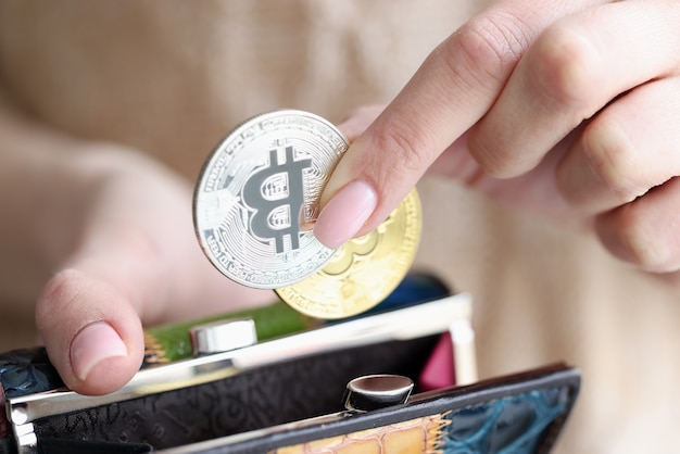 Female hand putting bitcoins into wallet closeup