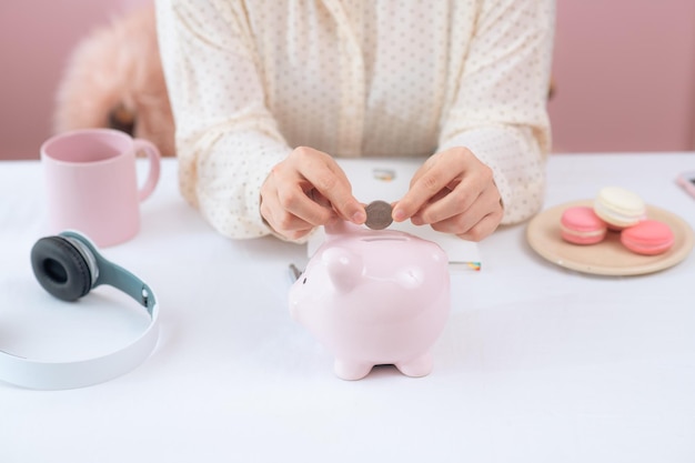 Female hand putting coin into piggy bank