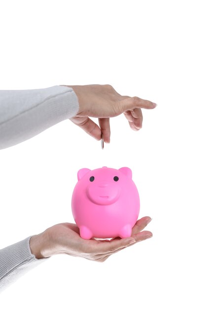 Female hand putting a coin into piggy bank