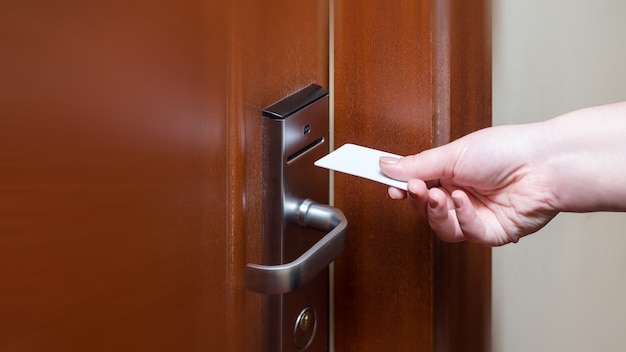 Mano femminile che mette la scheda chiave per aprire la porta della camera d'albergo.