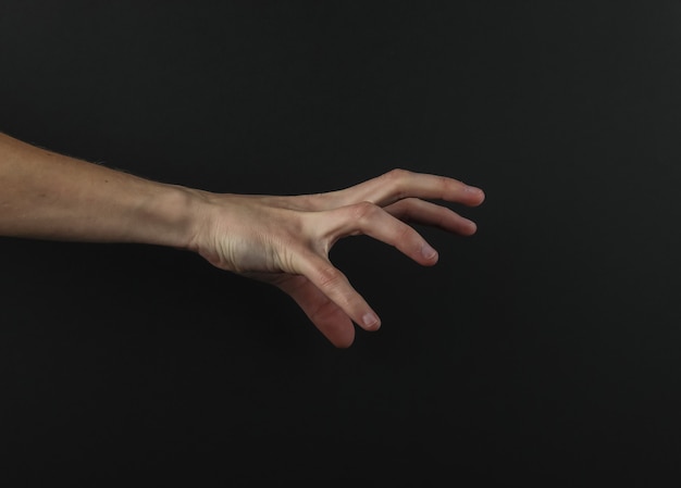 Photo female hand reaches for something on a black background