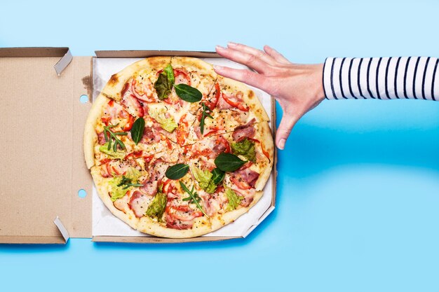Female hand reaching for a slice of pizza