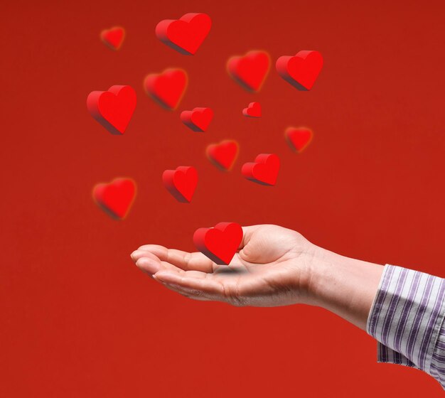 Female hand and red flying hearts on a red background happy valentines day