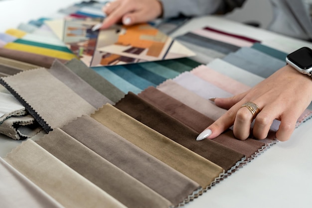 female hand show fabric catalog for choose bright rich color for new sofa