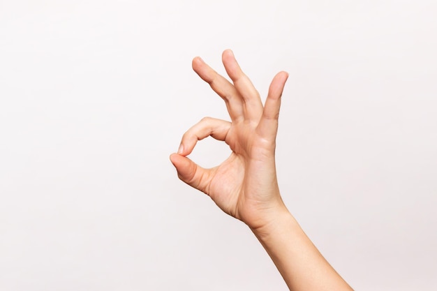 Female hand showing the ok gesture isolated on a white background Okey hand sign