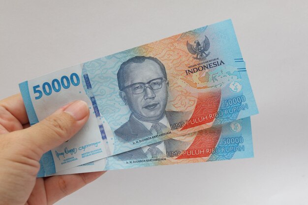 Foto una mano femminile che mostra due pezzi di denaro indonesiano di 50000 rupie