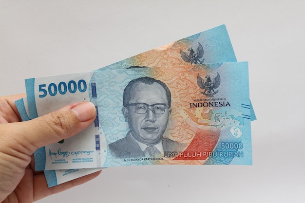 Photo a female hand showing two pieces indonesian money of 50000 rupiah