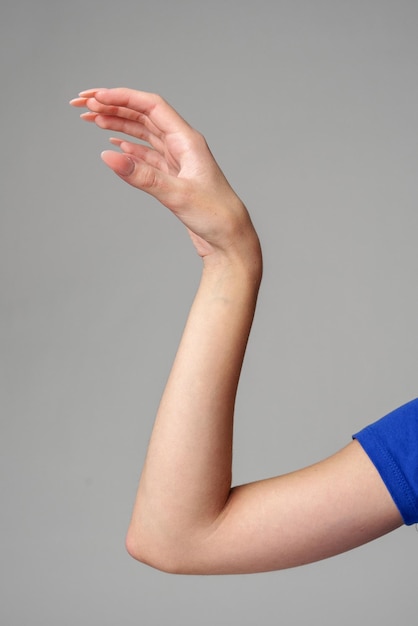 Фото Женский знак руки на сером фоне в студии