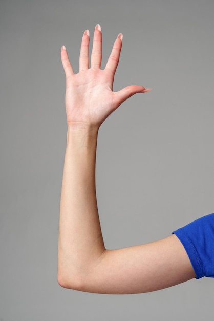 Female hand sign against gray background in studio