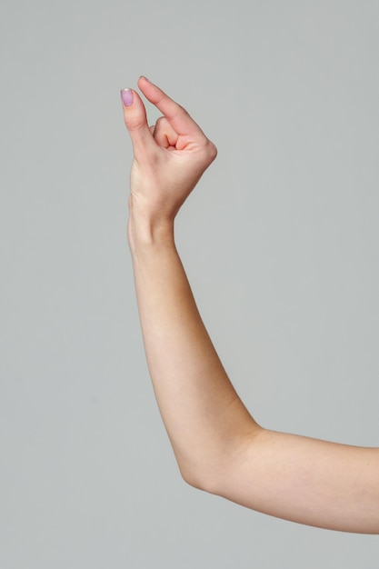 Photo female hand sign against gray background in studio