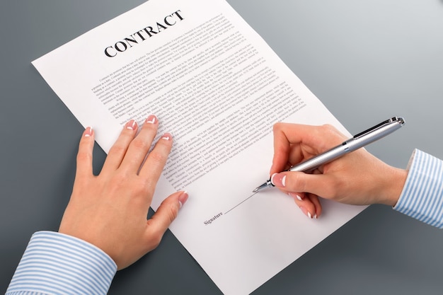 Female hand signs loan contract. Woman&amp;#39;s hand signing loan contract. I have no choice. This is very risky.